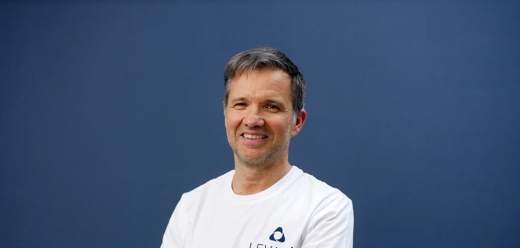 Stefan Rascher, Gründer von LEVANA, im LEVANA-Shirt vor blauem Hintergrund.